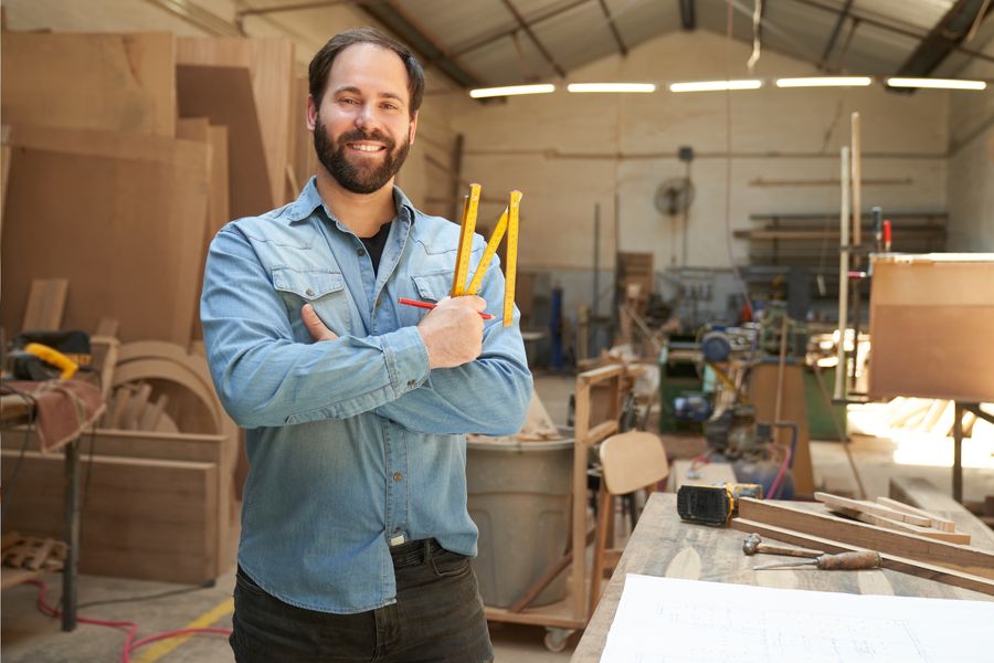 Schreiner mit Zollstock in seiner Werkstatt