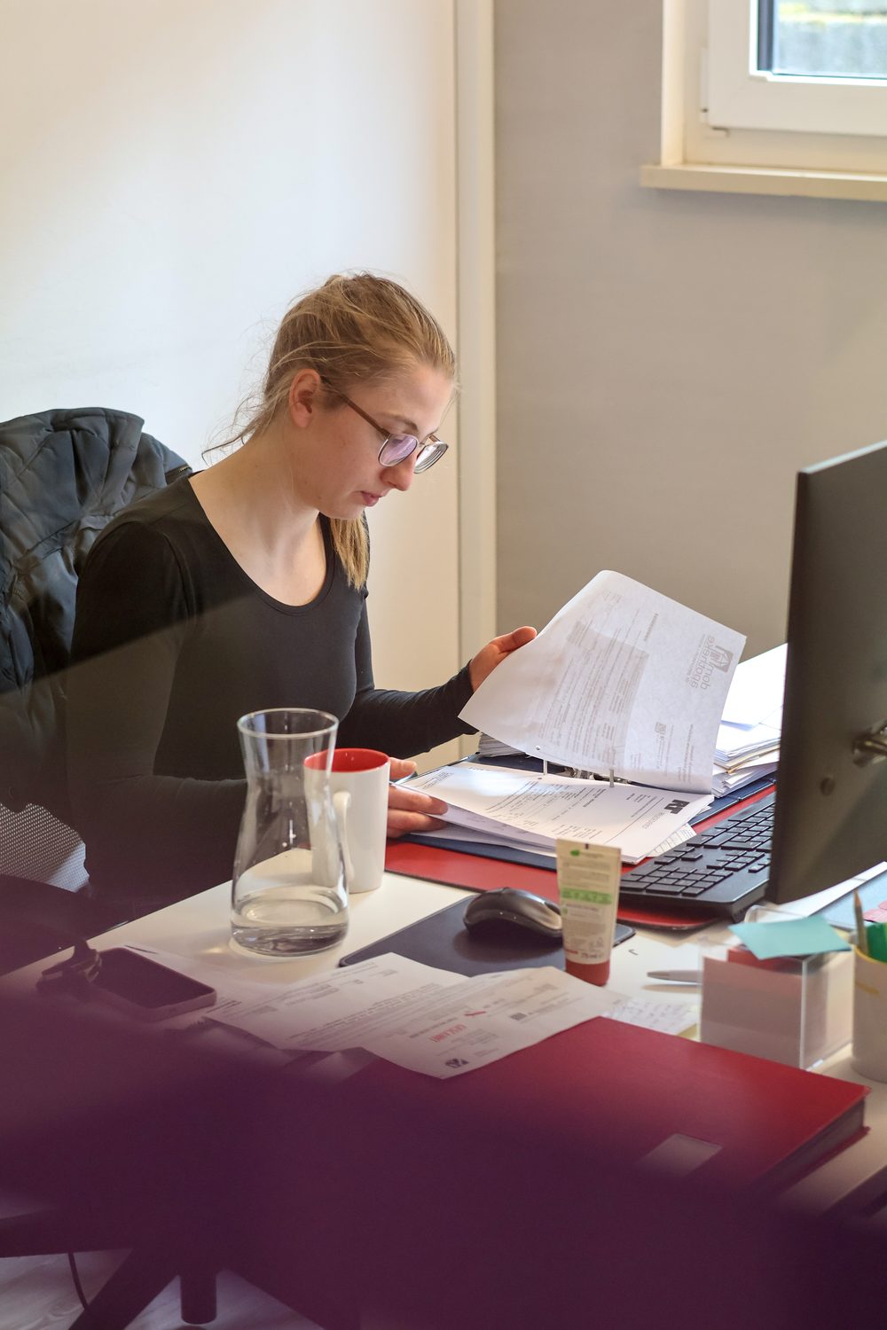 Mitarbeiterin bei der Durchsicht von Unterlagen am Arbeitsplatz